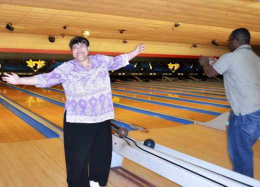 Woman with her arms outstretched in victory at a bowling lane 