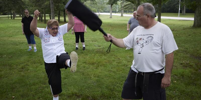 Access Point RI older woman participating in a martial arts exercise with male instructor.
