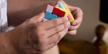 A person's hands are shown working with a cube puzzle