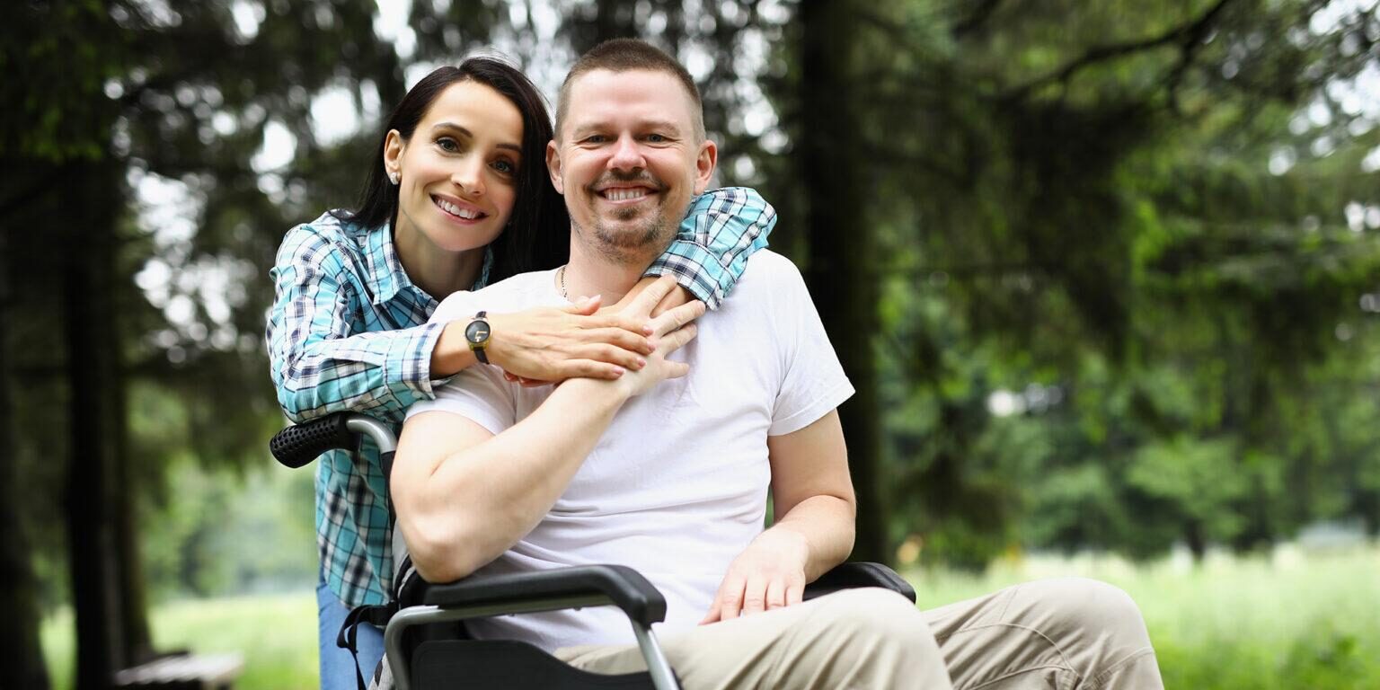 Man in wheelchair with woman caregiver showing support
